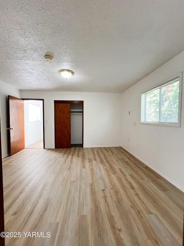 63 W Mead Ave, Yakima, WA 98902 - unfurnished bedroom with light wood-type flooring, a closet, a textured ceiling, and baseboards