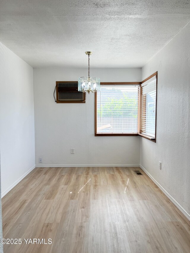 63 W Mead Ave, Yakima, WA 98902 - spare room featuring wood finished floors, a chandelier, baseboards, a textured ceiling, and a wall unit AC