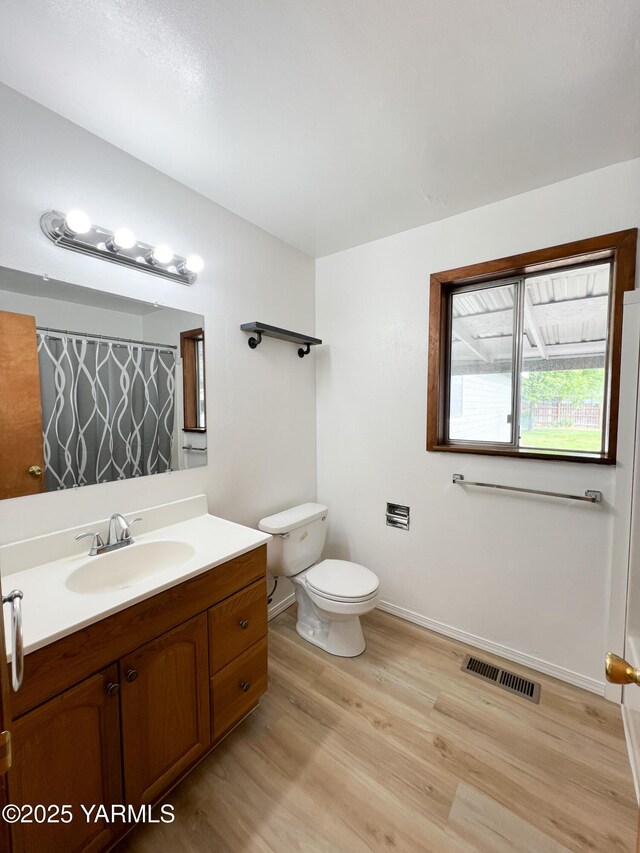 63 W Mead Ave, Yakima, WA 98902 - full bathroom featuring wood finished floors, vanity, toilet, baseboards, and curtained shower