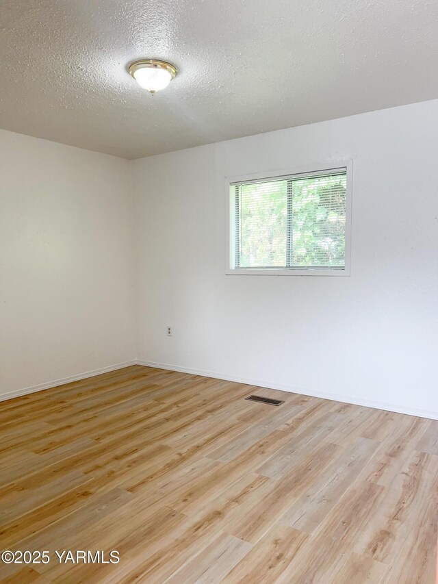 63 W Mead Ave, Yakima, WA 98902 - empty room with light wood-type flooring, a textured ceiling, and baseboards
