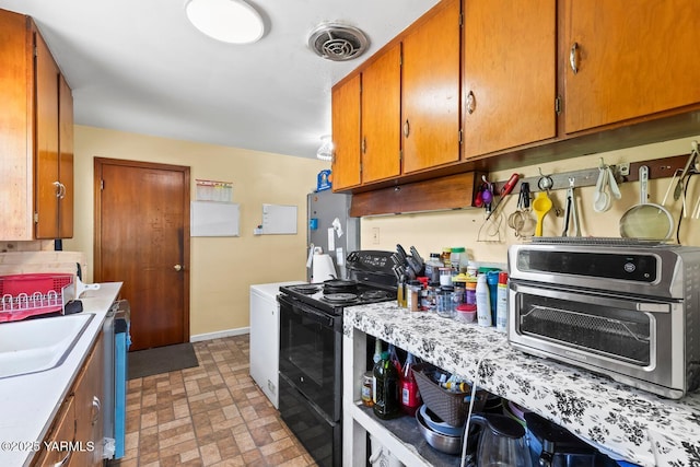 1306 S 6th Ave, Yakima, WA 98902 - kitchen featuring black electric range oven, light countertops, brown cabinets, brick patterned floors, and dishwasher