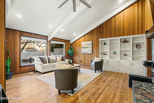 living area featuring lofted ceiling with beams, recessed lighting, wooden walls, a ceiling fan, and light wood-style floors