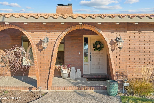 entrance to property with a chimney and brick siding