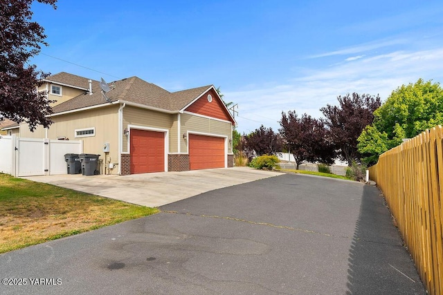 815 Trout Lake Ct, Yakima, WA 98901 - view of property exterior with an attached garage, asphalt driveway, a gate, roof with shingles, and brick siding