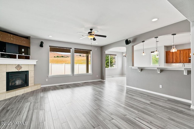 815 Trout Lake Ct, Yakima, WA 98901 - unfurnished living room with ceiling fan, wood finished floors, a tiled fireplace, arched walkways, and recessed lighting