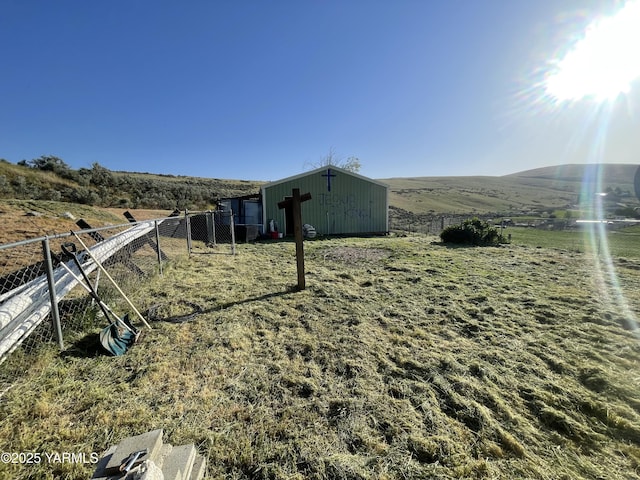 view of yard featuring an outdoor structure, fence, an outbuilding, and a rural view