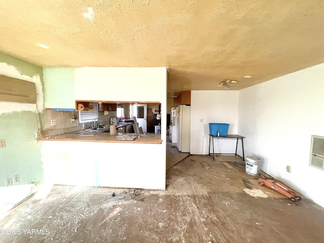 kitchen with a sink, a textured ceiling, and freestanding refrigerator
