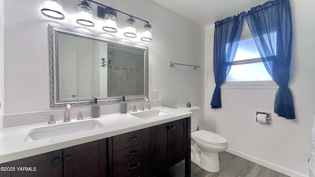 full bath featuring double vanity, wood finished floors, a sink, and toilet