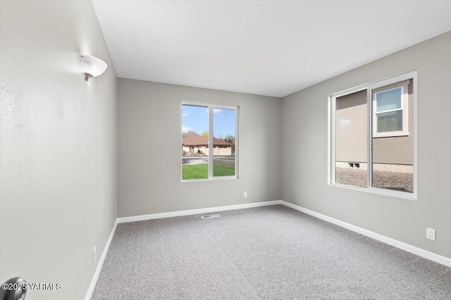 empty room featuring visible vents, baseboards, and carpet