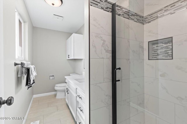 bathroom with a shower stall, toilet, vanity, and baseboards