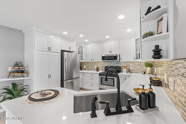 kitchen featuring backsplash, white cabinetry, glass insert cabinets, light countertops, and appliances with stainless steel finishes
