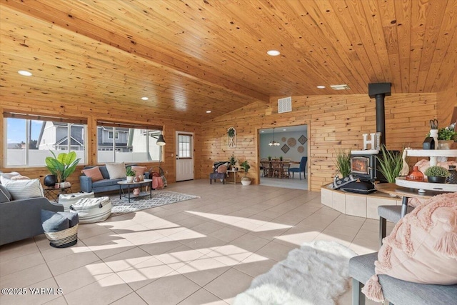 tiled living area with wood ceiling, a wood stove, vaulted ceiling with beams, and wooden walls