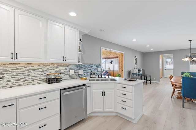 kitchen featuring a peninsula, dishwasher, a sink, and tasteful backsplash