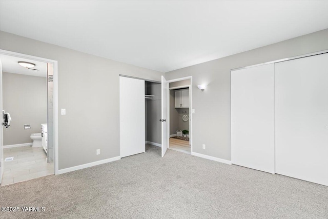 unfurnished bedroom featuring multiple closets, baseboards, and carpet