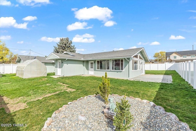back of house with a patio area, a fenced backyard, a greenhouse, and a yard