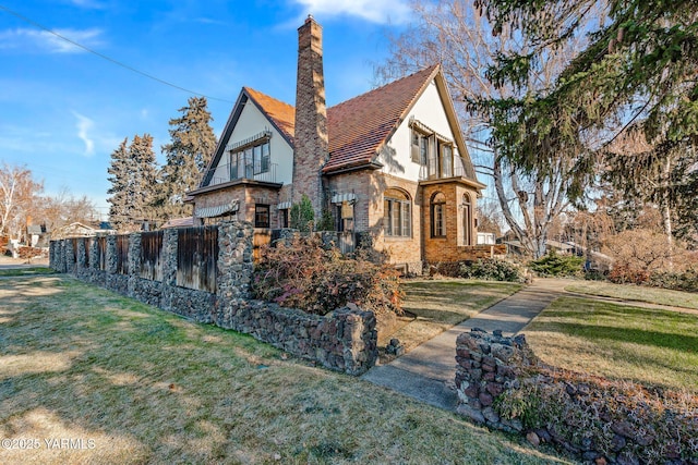 view of side of property with a chimney, fence, and a yard