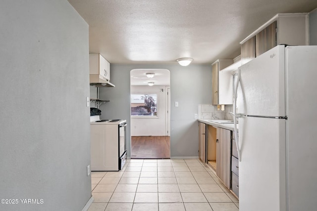 kitchen featuring light tile patterned floors, light countertops, electric range, freestanding refrigerator, and under cabinet range hood