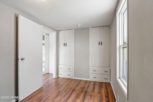 unfurnished bedroom featuring baseboards and dark wood-type flooring