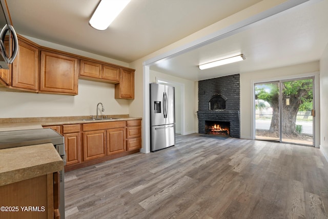 1000 Franklin Rd, Tieton, WA 98947 - kitchen with stainless steel fridge, a sink, light wood-style floors, a fireplace, and brown cabinetry