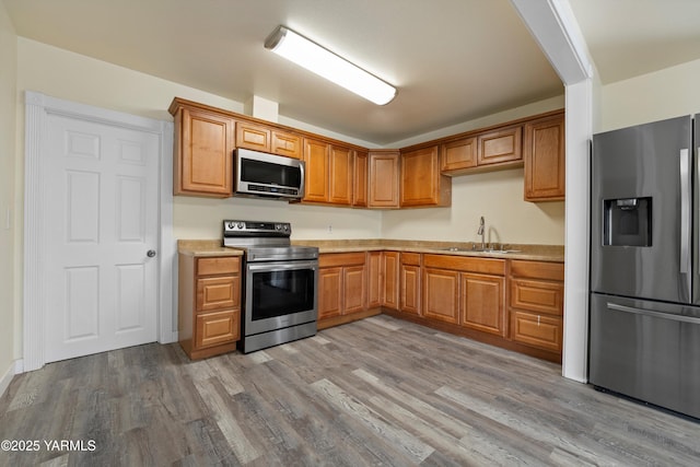 1000 Franklin Rd, Tieton, WA 98947 - kitchen featuring appliances with stainless steel finishes, a sink, light countertops, wood finished floors, and brown cabinets