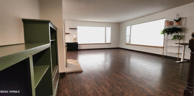 spare room with a textured ceiling, baseboards, and dark wood-type flooring