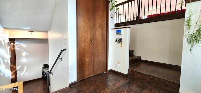 interior space featuring dark wood-style floors, stairway, a textured ceiling, and baseboards