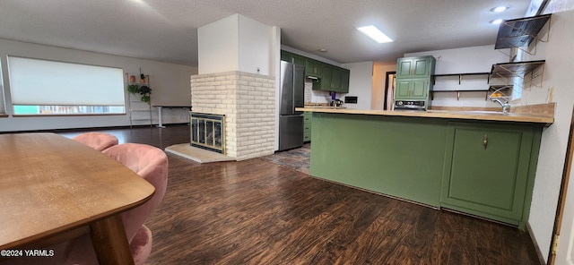 kitchen with refrigerator, a peninsula, light countertops, open shelves, and green cabinetry