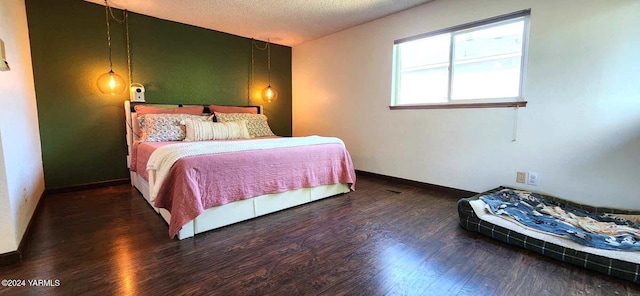 bedroom with dark wood-style flooring, a textured ceiling, and baseboards