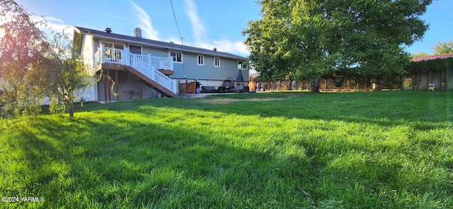 rear view of property with a yard, a wooden deck, and stairs