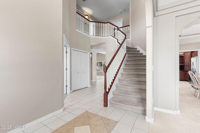 staircase with a high ceiling, tile patterned flooring, and baseboards