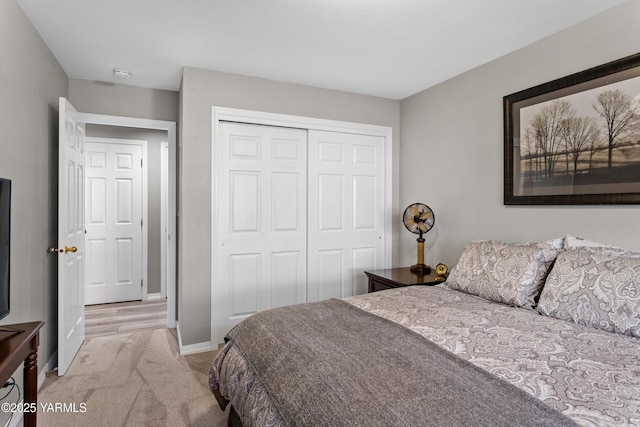 bedroom with baseboards, a closet, and light colored carpet