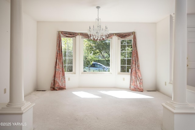 unfurnished dining area with visible vents, an inviting chandelier, decorative columns, and light colored carpet