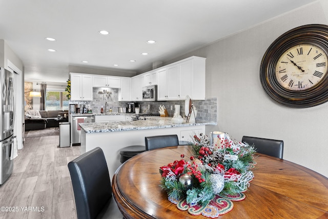 dining space with light wood finished floors and recessed lighting