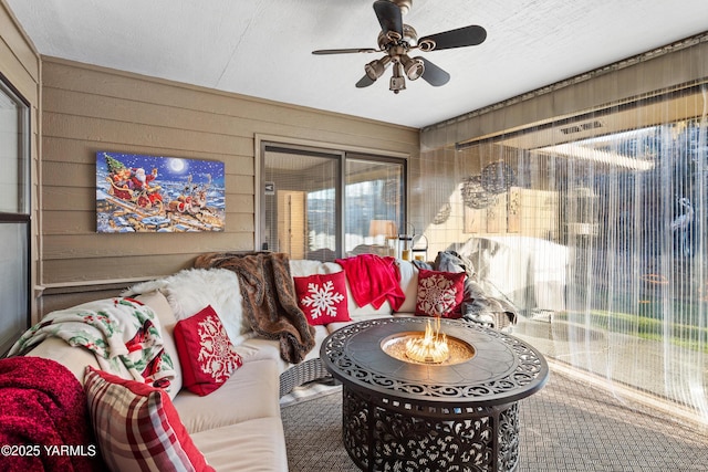 living area with wood walls, a textured ceiling, and ceiling fan