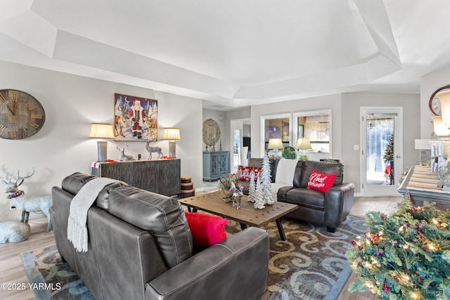 living room with a tray ceiling and wood finished floors