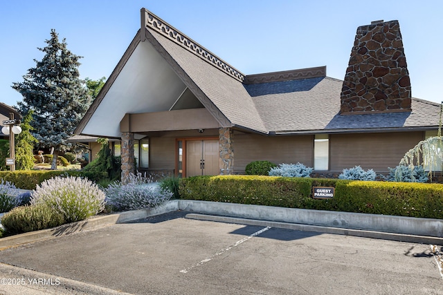 view of front facade with uncovered parking and roof with shingles