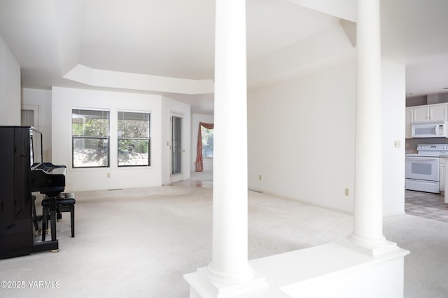 living room featuring a raised ceiling, light carpet, and ornate columns