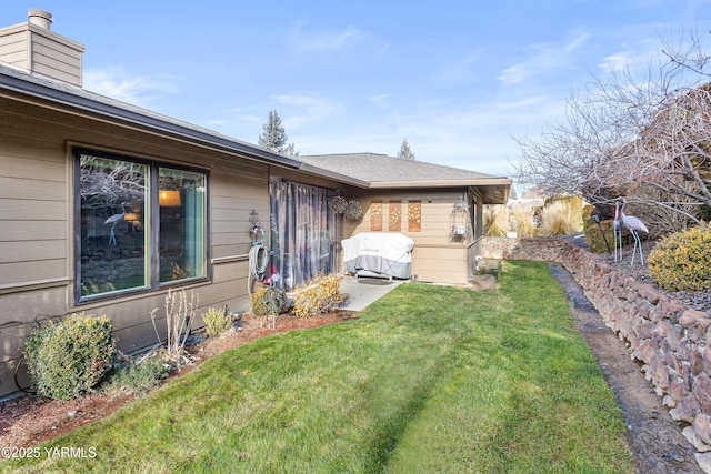 view of property exterior featuring a lawn, a chimney, and fence