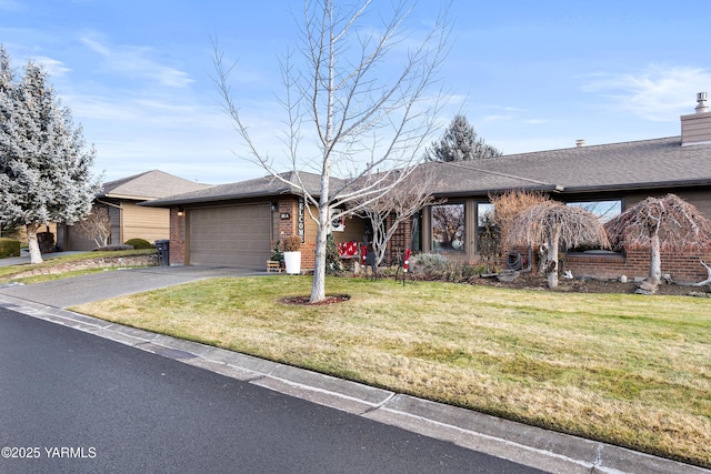 view of front of home with a shingled roof, brick siding, driveway, and a front lawn