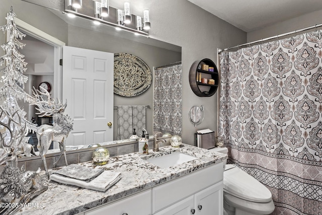 bathroom with toilet, a textured wall, and vanity