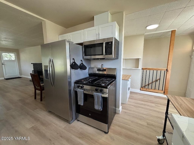 407 S 17th Ave, Yakima, WA 98902 - kitchen featuring appliances with stainless steel finishes, light wood finished floors, white cabinetry, and baseboards
