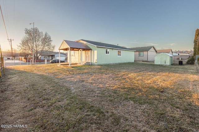 back of house with a storage shed, a yard, fence, and an outbuilding