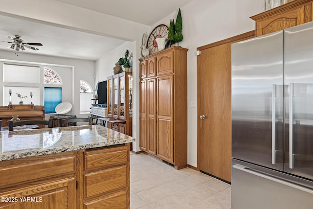 6 N 78th Ave, Yakima, WA 98908 - kitchen with high quality fridge, a ceiling fan, light stone counters, brown cabinetry, and light tile patterned floors