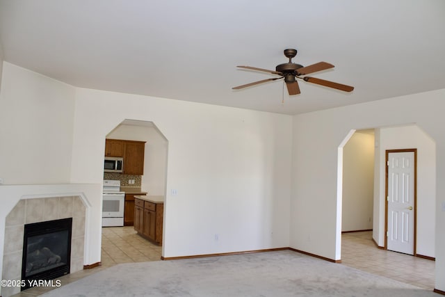 408 S 93rd Ave, Yakima, WA 98908 - unfurnished living room with a ceiling fan, arched walkways, baseboards, and a fireplace