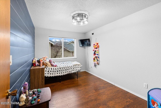 bedroom featuring wood finished floors, baseboards, and a textured ceiling