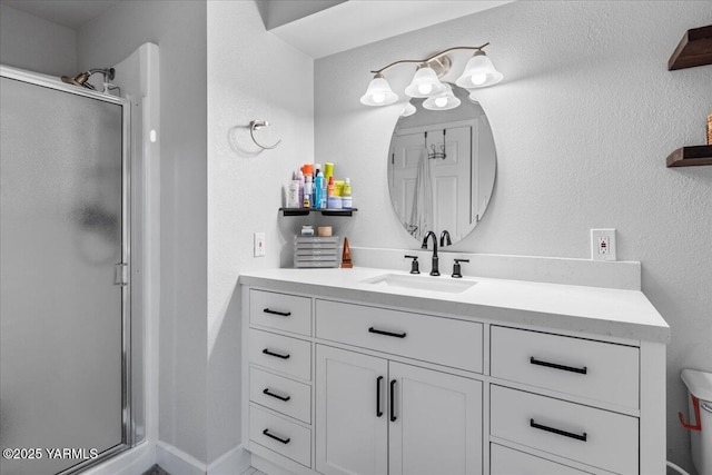 full bathroom with vanity, a textured wall, and a stall shower