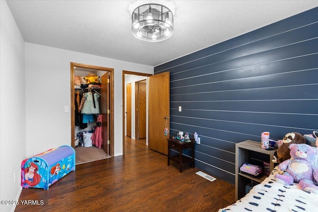 bedroom with wood finished floors, visible vents, a spacious closet, a closet, and a textured ceiling