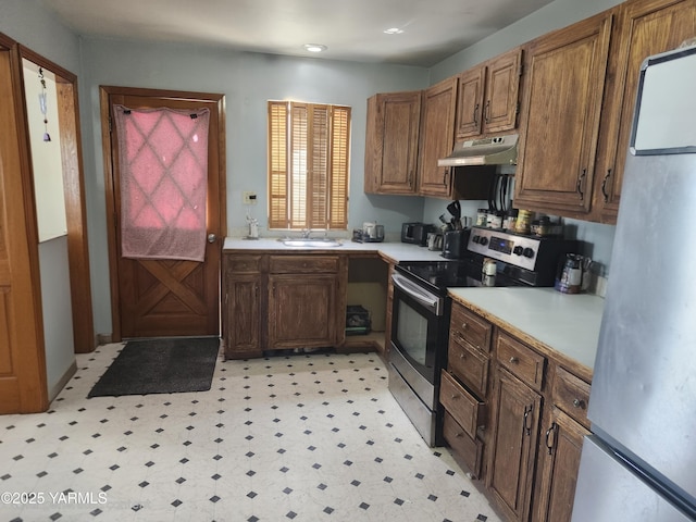 1202 W Viola Ave, Yakima, WA 98902 - kitchen with stainless steel appliances, under cabinet range hood, light countertops, light flooring, and brown cabinetry