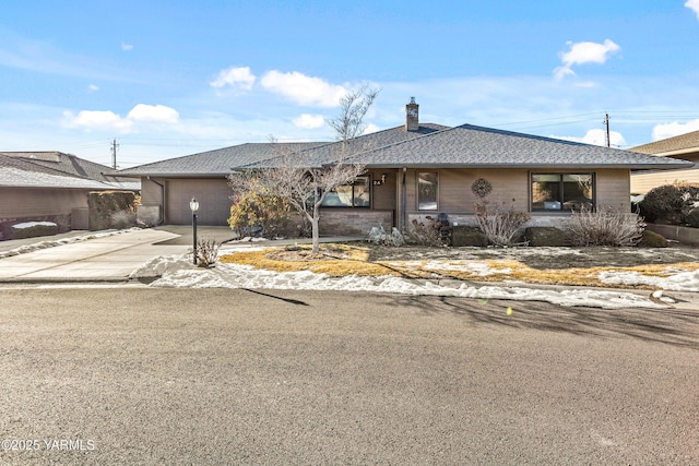 ranch-style home featuring an attached garage, a shingled roof, and concrete driveway