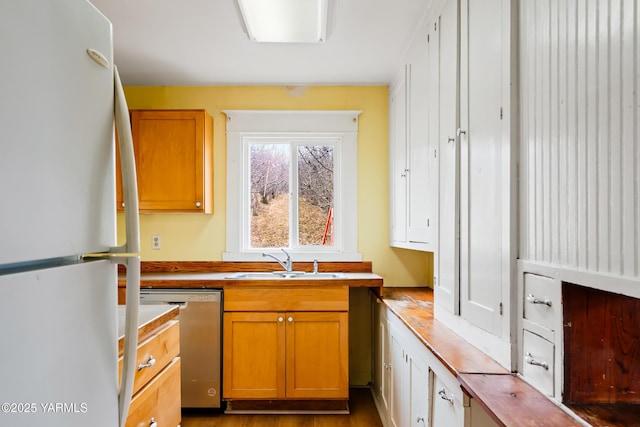 1555 W Tieton Rd, Tieton, WA 98947 - kitchen with freestanding refrigerator, stainless steel dishwasher, a sink, and brown cabinets